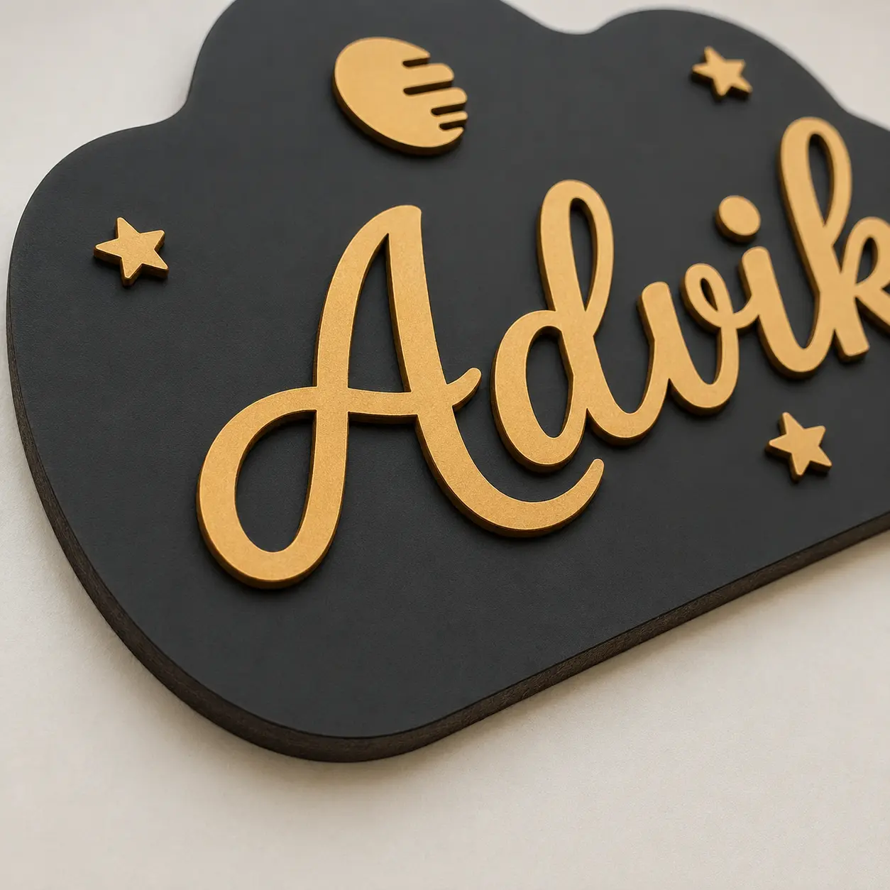 Close-up of matte black MDF kids room name board with raised gold Advik lettering and laser-cut edge