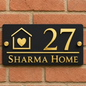 Matte black and shiny gold acrylic house number plate showing 27 and Sharma Home